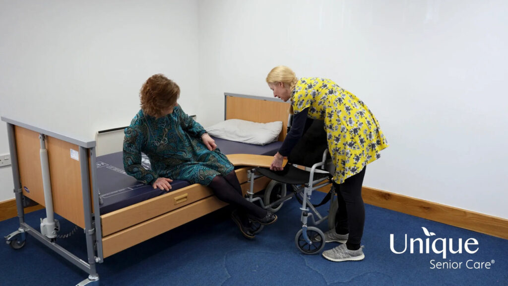 helping an elderly from bed to wheelchair using transfer board